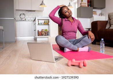 Young African America Woman At Home Doing Exercise In Front Of Open Laptop, Repeating Instructions By Professional Online Fitness Trainer.