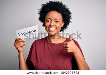Young African American afro politician woman with curly hair socialist party member happy with big smile doing ok sign, thumb up with fingers, excellent sign