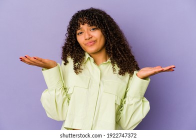 Young african american afro woman isolated doubting and shrugging shoulders in questioning gesture.