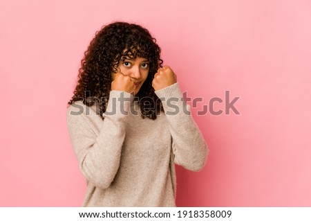 Young african american afro woman isolated throwing a punch, anger, fighting due to an argument, boxing.