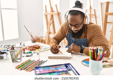 Young african american artist man using headphones drawing at art studio. - Powered by Shutterstock