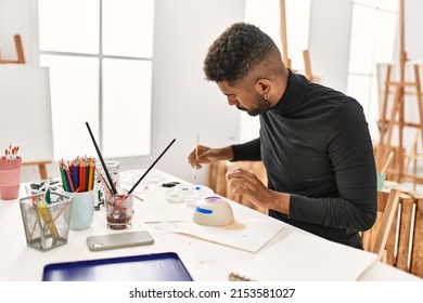 Young african american artist man concentrated painting pottery at art studio. - Powered by Shutterstock