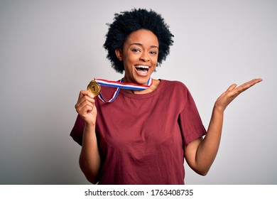 Young African American athlete woman with curly hair wearing gold medal winner competition very happy and excited, winner expression celebrating victory screaming with big smile and raised hands - Powered by Shutterstock