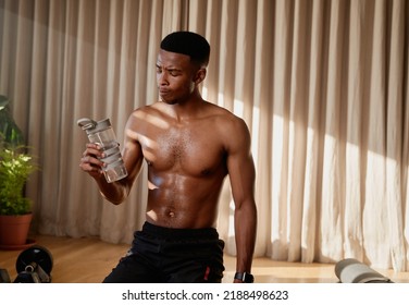 Young African American Black Male Athlete Drinking Water After A High Intensity Exercise Workout At Home Doing An Online Class. Keeping Fit And Healthy 