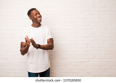 Young African American Black Man Feeling Happy And Successful, Smiling And Clapping Hands, Saying Congratulations With An Applause Against Brick Wall