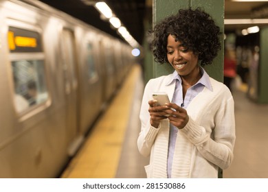 Young African American Black Woman Texting On Cell Phone In Subway Station