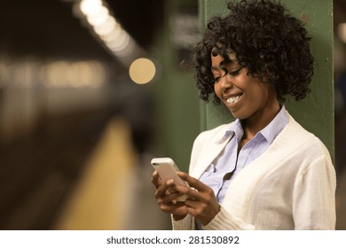 Young African American Black Woman Texting On Cell Phone In Subway Station