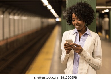 Young African American Black Woman Texting On Cell Phone In Subway Station