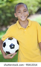 A Young African American Boy Child Outside Playing Holding Soccer Or Football