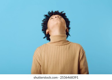 Young african american boy gazing upward, searching for inspiration and dreaming underneath a vast blue sky - Powered by Shutterstock