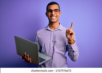 Young african american business man working using laptop over purple background surprised with an idea or question pointing finger with happy face, number one