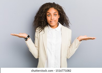 Young African American Business Woman Confused And Doubtful Shrugging Shoulders To Hold A Copy Space.