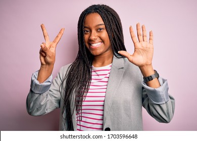 Young african american business woman standing over pink isolated background showing and pointing up with fingers number seven while smiling confident and happy.