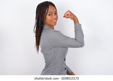 Young African American Business Woman With Braids Over White Wall,  Showing Muscles After Workout. Health And Strength Concept.