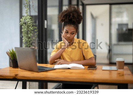 Young african american business woman waiting message from mobile during working. Lack of concentration at work.