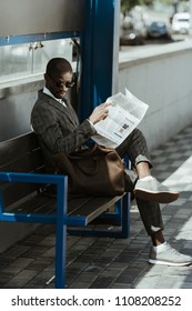 Young african american businessman with newspaper resting on bench - Shutterstock ID 1108208252