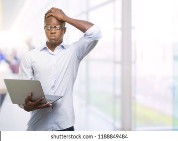 Young African American Businessman Using Computer Laptop Stressed With Hand On Head, Shocked With Shame And Surprise Face, Angry And Frustrated. Fear And Upset For Mistake.