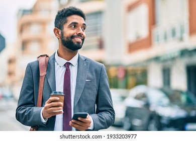 Young african american businessman using smartphone and drinking take away coffee at the city.