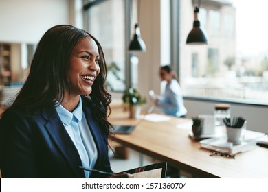 Young African American businesswoman laughing while walking in an office after a meeting with colleagues