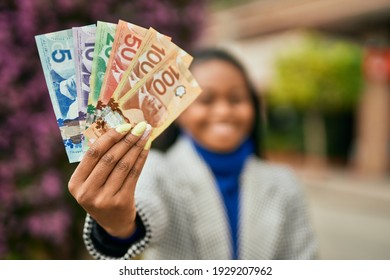 Young african american businesswoman smiling happy holding canadian dollars at the city.
