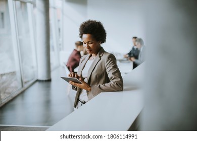 Young African American businesswoman standing and using digital tablet in the modern office - Powered by Shutterstock