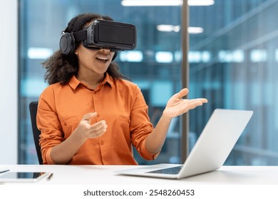 Young African American businesswoman using virtual reality headset while interacting with laptop in modern office. Emphasis on innovation, technology, and professional experience. - Powered by Shutterstock