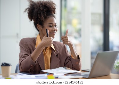 Young African American businesswoman working on laptop computer with pile of documents at office workplace, business finance and accounting concepts. - Shutterstock ID 2254145151