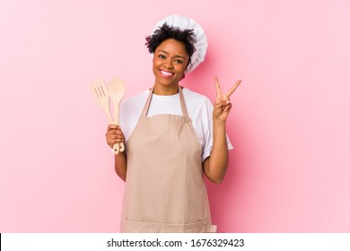 Young African American Cook Woman Joyful And Carefree Showing A Peace Symbol With Fingers.