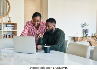 Young African American couple doing some online banking together at their dining room table at home - Powered by Shutterstock