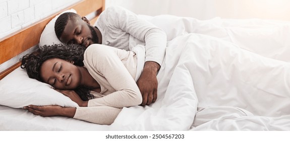 Young african american couple napping together in bed, husband cuddling his wife from back. - Powered by Shutterstock