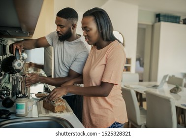 Young African American Couple Preparing Breakfast And Making Coffee Together While Standing At Their Kitchen Counter In The Morning