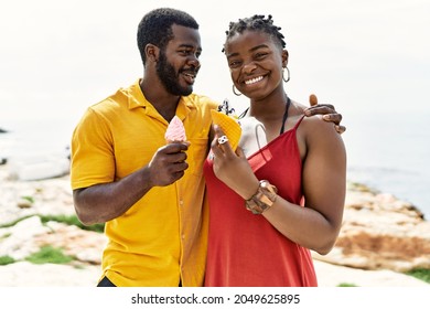 Young African American Couple Smiling Happy Eating Ice Cream At The Beach.