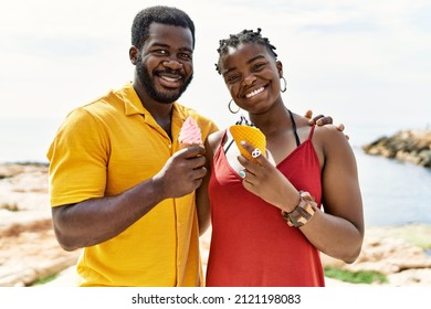 Young African American Couple Smiling Happy Eating Ice Cream At The Beach.