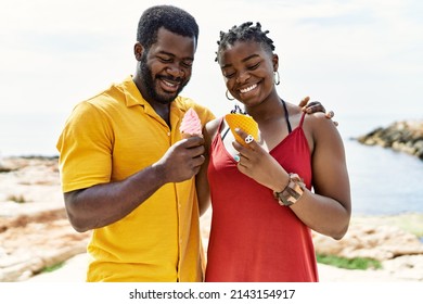 Young African American Couple Smiling Happy Eating Ice Cream At The Beach.