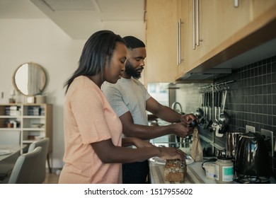 Young African American Couple Standing Together At Their Kitchen Counter In The Morning Preparing Breakfast And Making Coffee