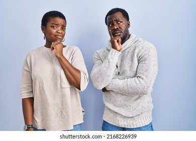 Young African American Couple Standing Over Blue Background Together Thinking Worried About A Question, Concerned And Nervous With Hand On Chin 