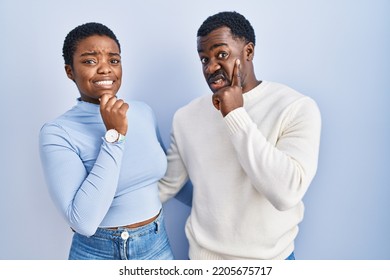 Young African American Couple Standing Over Blue Background Thinking Worried About A Question, Concerned And Nervous With Hand On Chin 