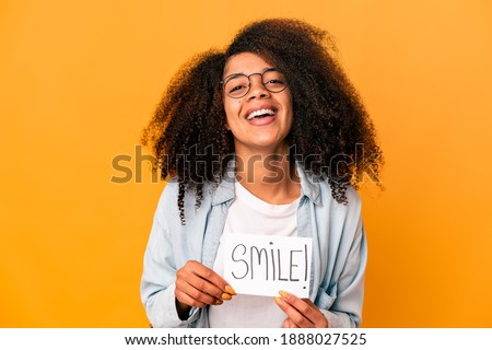 Young african american curly woman holding a smile message placard laughing and having fun.