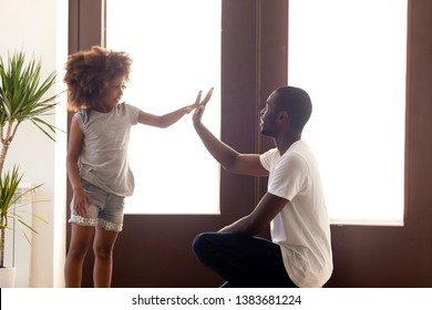 Young African American Dad Give High Five To Small Cute Daughter In Hallway, Black Father And Little Kid Make Deal Talking At Home, Parent Negotiate With Child Having Agreement. Friendship Concept