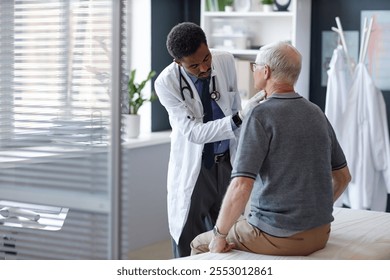 Young African American doctor examining senior patient in clinic and palpating neck for lymph node or thyroid problems, copy space - Powered by Shutterstock