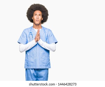 Young african american doctor man with afro hair begging and praying with hands together with hope expression on face very emotional and worried. Asking for forgiveness. Religion concept. - Shutterstock ID 1446428273