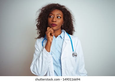 Young African American Doctor Woman Wearing Stethoscope Over Isolated White Background With Hand On Chin Thinking About Question, Pensive Expression. Smiling With Thoughtful Face. Doubt Concept.