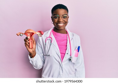 Young african american doctor woman holding anatomical model of female genital organ looking positive and happy standing and smiling with a confident smile showing teeth 