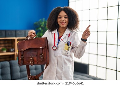 Young African American Doctor Woman Holding Bag For Home Assistance Smiling Happy Pointing With Hand And Finger To The Side 