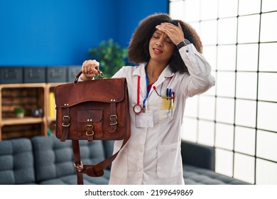 Young African American Doctor Woman Holding Bag For Home Assistance Stressed And Frustrated With Hand On Head, Surprised And Angry Face 