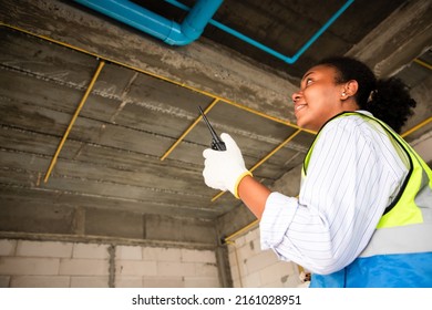 Young African American Engineer And Architect Working At Construction Site With Calculate Spending Report Inside House. Real Estate Project With Civil Engineer. Power Line Inspection