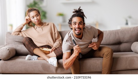 Young African American Family Couple Disagree On Tv Channel Choice, Excited Black Man Watching Football Match, Holding Remote Control And Ignoring Annoyed Bored Girlfriend,sitting Together On Sofa