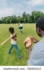 Young African American Family With One Child Playing Baseball On Green Lawn