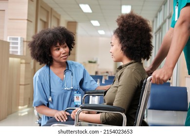 Young African American Female Doctor With Stethoscope In Uniform Checks Injury Patient Girl In Wheelchair At Outpatient Accident Clinic Hospital, Illness Medical Clinic Examination, Healthcare Hall.