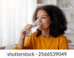 Young African American Female Drinking Clean Mineral Water From Glass At Home, Healthy Beverage, Thirsty Black Woman Taking Care About Body Hydration, Closeup Shot, Side View With Free Space